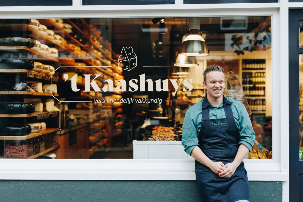 De etalage van 't Kaashuys aan de Dorpsstraat, met Mike ervoor